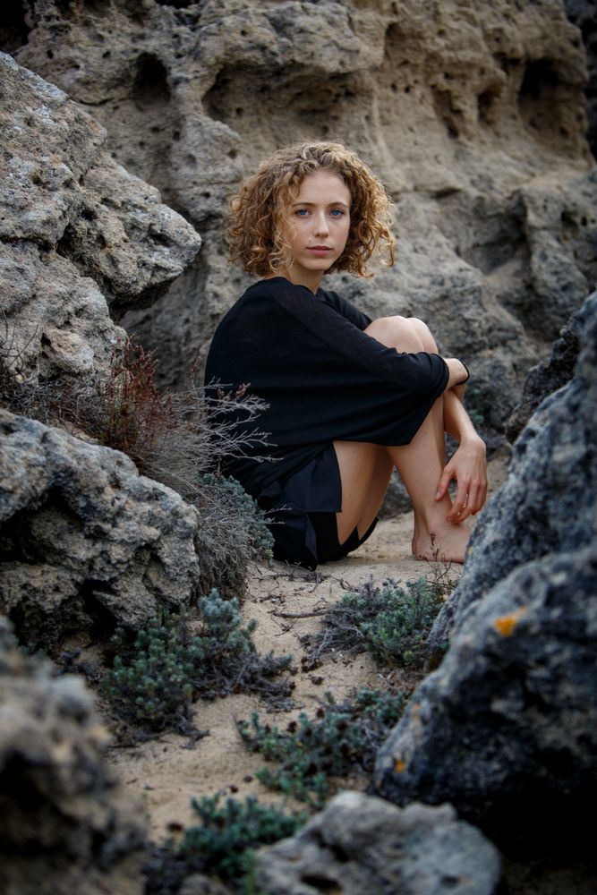 Young woman sitting between stones