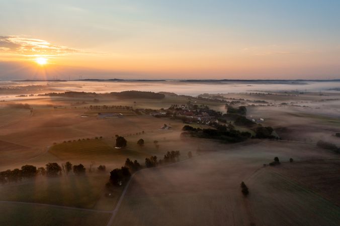 Drone shot at golden hour with foggy rolling agricultural fields