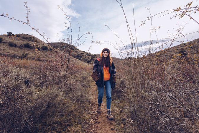 Hiker with backpack walking along pathway in autumn forest
