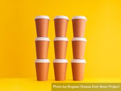 Stack of disposable coffee cups on yellow background 5nEd80