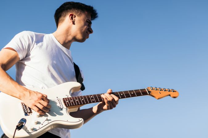 man playing electric guitar outdoors.blue sky background
