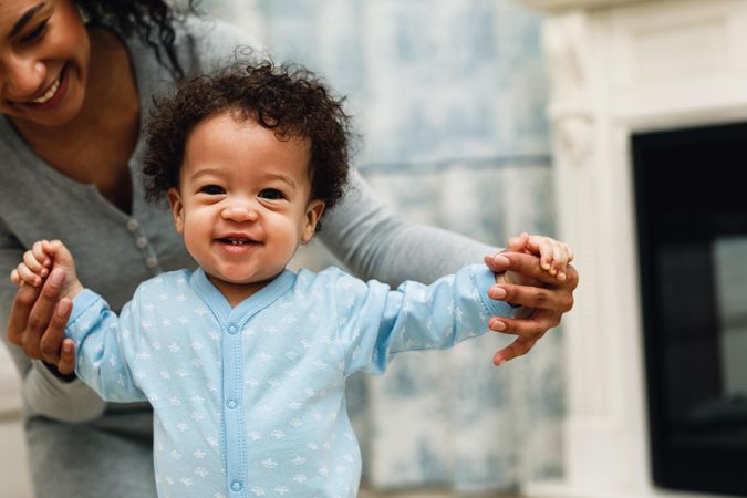 Smiling toddler walking with mother’s help