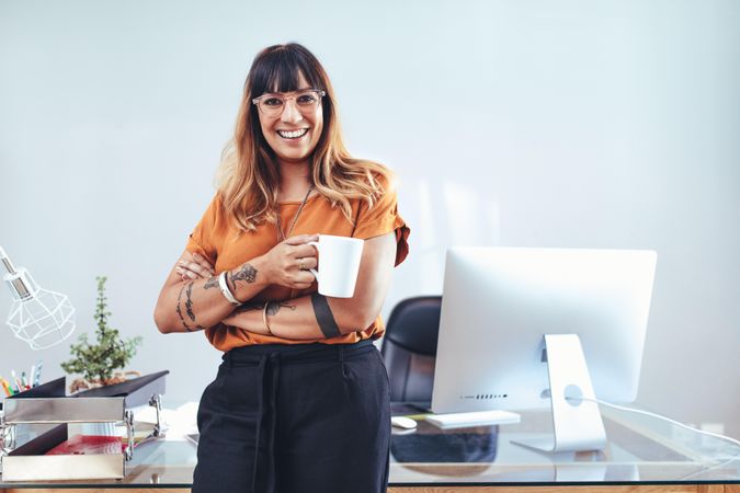 Smiling businesswoman standing with a coffee cup in hand