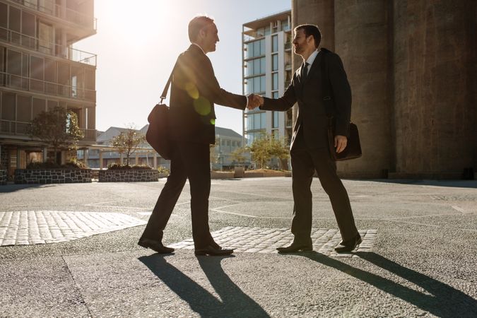 Business colleagues meeting each other on a street while commuting to office