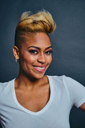 Smiling Black woman with short blonde hair in gray studio