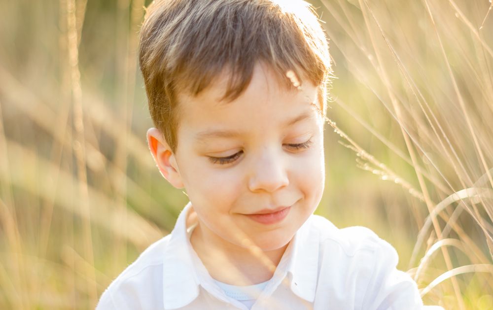 Kid in field playing with spikes at summer sunset