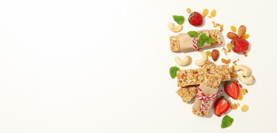 Granola bars, strawberry and nuts on blank background, space for text