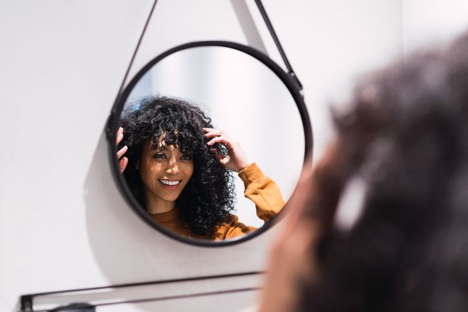 Smiling Black woman looking at mirror at home