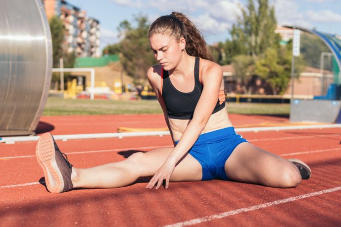 Female athlete stretching on an athletics track.