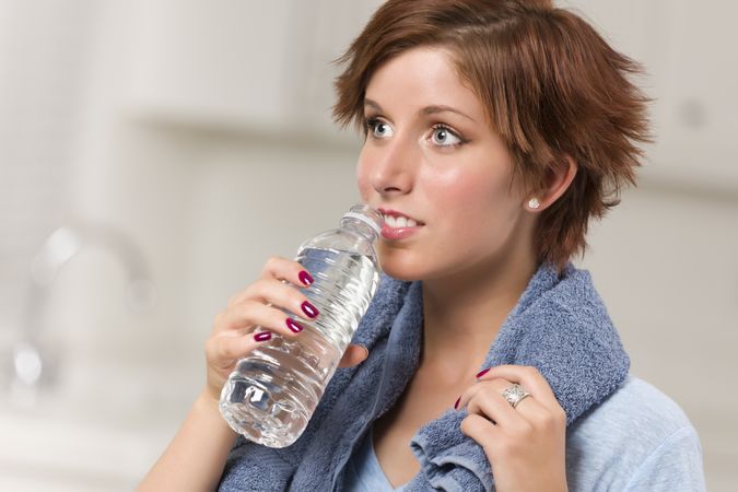 Red Haired Woman with Towel Drinking From Water Bottle