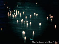Lit paper lanterns floating on water at night bxrGd5