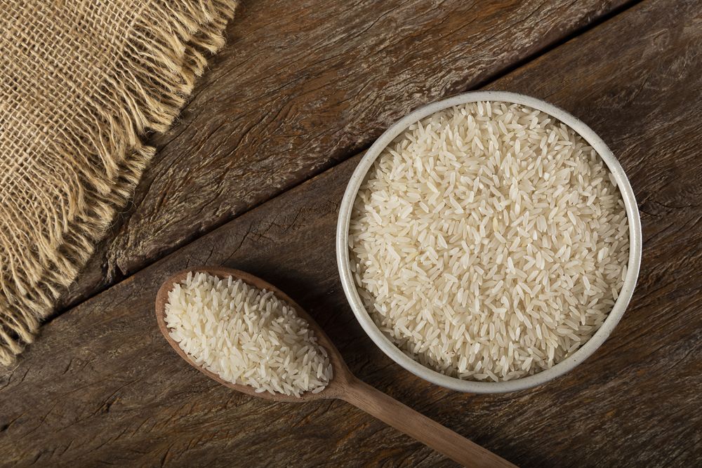 Rice in a ceramic bowl on brown wooden background.