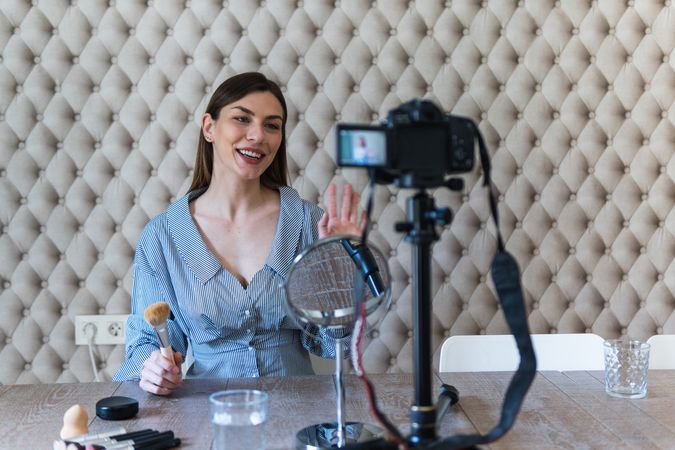 Happy woman applying powder and recording video on camera