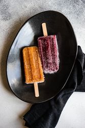 Two fruity ice cream pops on dark plate