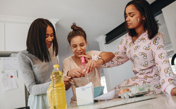 Girls making breakfast with milk and eggs in kitchen