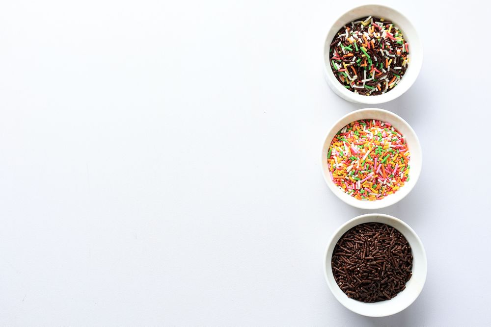 Chocolate and Rainbow Colored Sprinkles on Plain Background, Copy Space