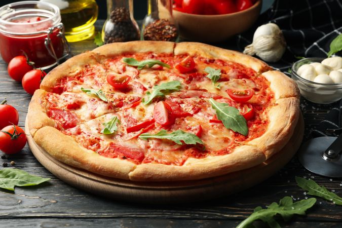 Tasty pizza and ingredients on wooden background