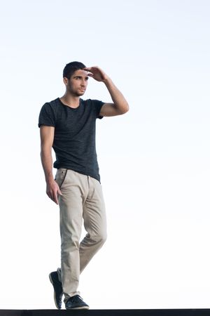 Full body portrait of male in t-shirt and slacks on light background, copy space
