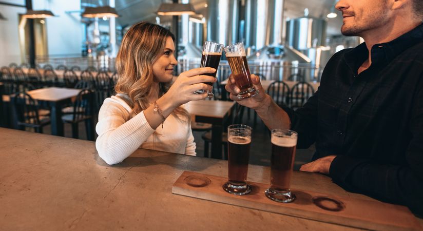 Young woman and man toasting with beer sample glasses