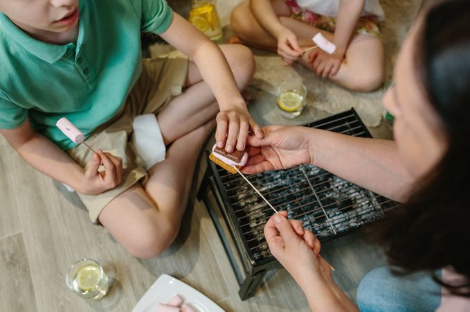 Top view of unrecognizable family making smores at home