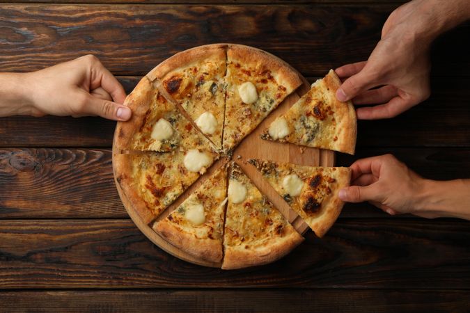 Hands hold slices of tasty cheese pizza, top view