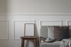 Blank wooden picture frame mockup on vintage side table, night stand next to linen midcentury sofa