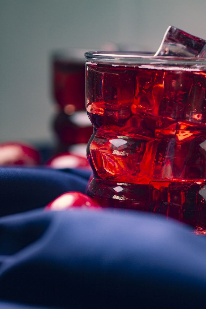 Red beverage near fresh fruits on cloth
