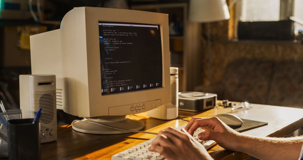 White Male College Student Using Old Desktop Computer In Nineties Retro Garage.