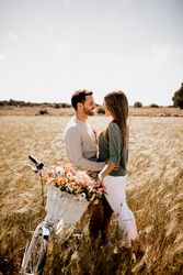 Sincere lovers posing by bicycle on rye field