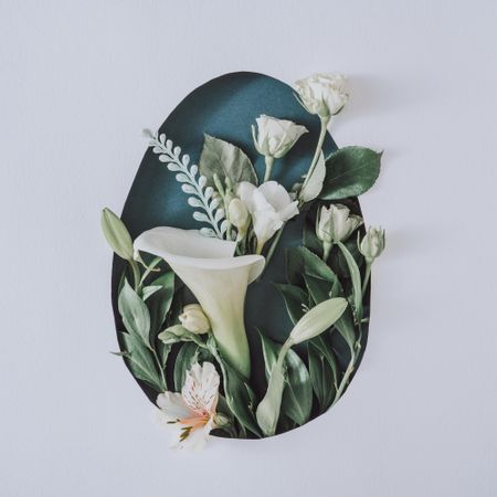 Easter layout with flowers and leaves in egg shape on light paper background