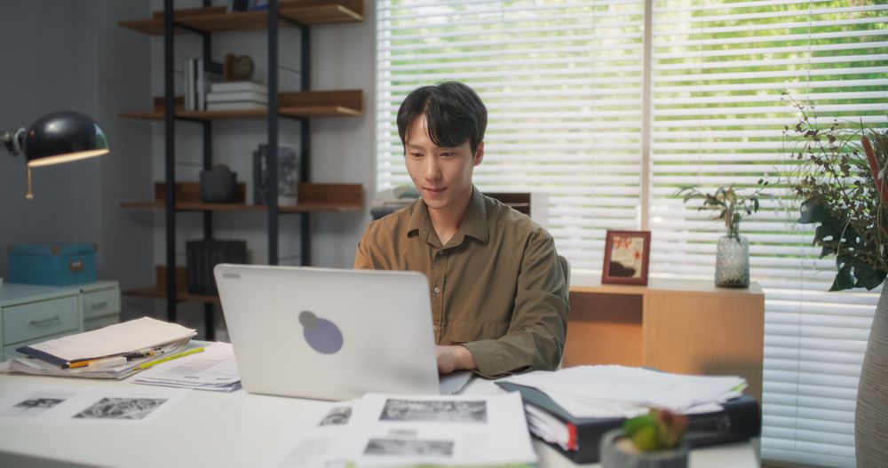 Young Korean Professional Working on Laptop Computer Behind a Desk at His Cozy Stylish Office.
