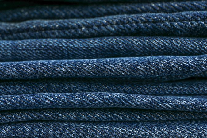 Stack of blue jeans as background, space for text