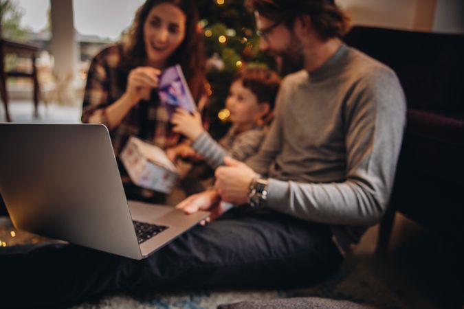 Family having a video call on laptop and showing gifts