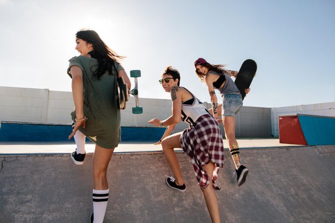 Happy female friends running over skateboard ramp