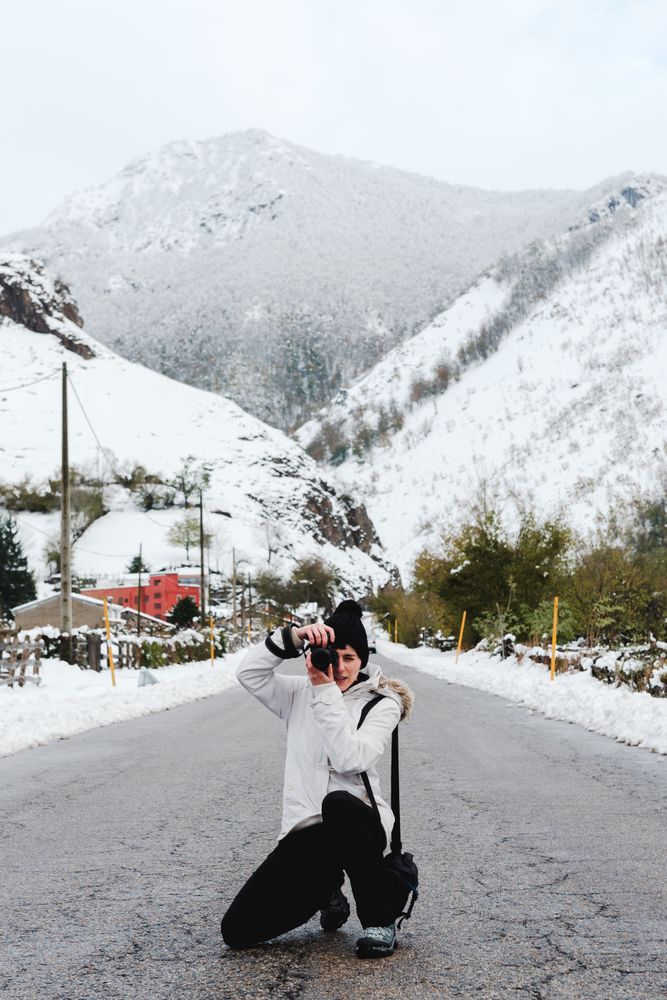 Content woman taking picture in snowy mountains