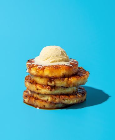 Summer dessert, grilled pineapple with vanilla ice cream, isolated on a blue background