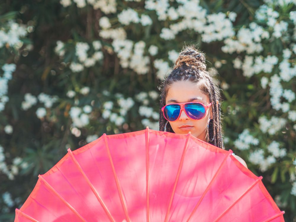 Fit young female with umbrella standing near blooming trees
