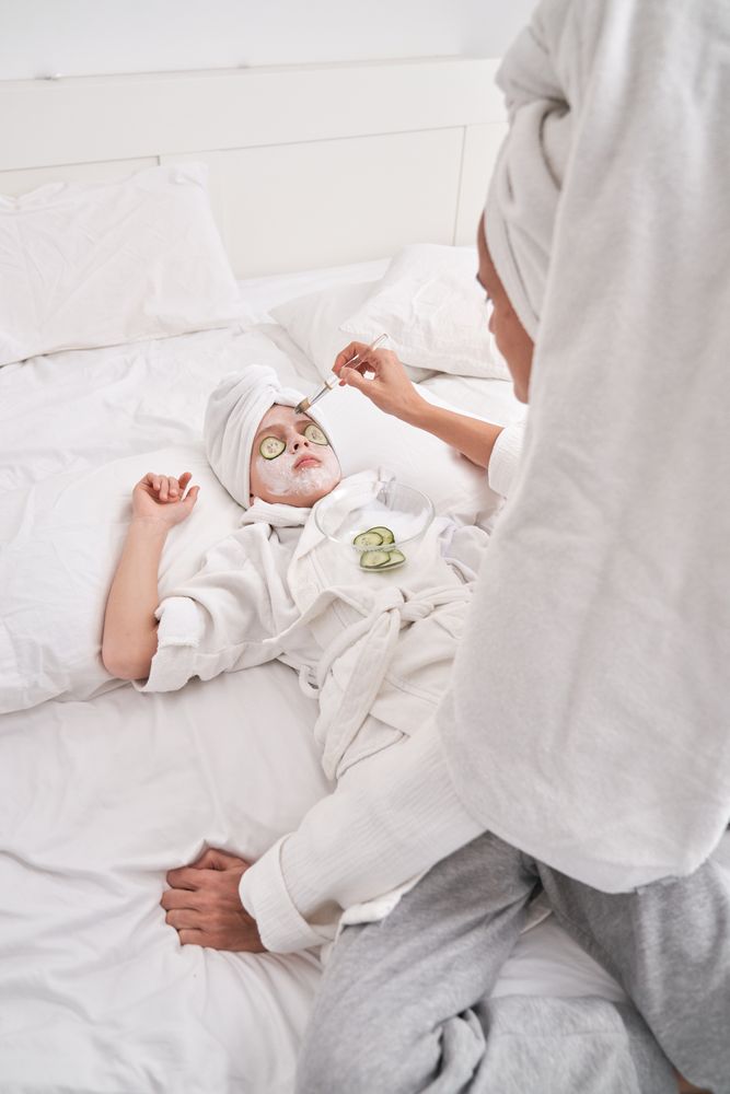 Mother applying facial mask on child during spa session