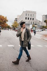 Busy male with smartphone crossing road