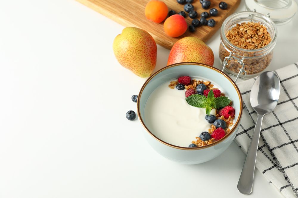 Composition with yogurt dessert and ingredients on blank background, space for text