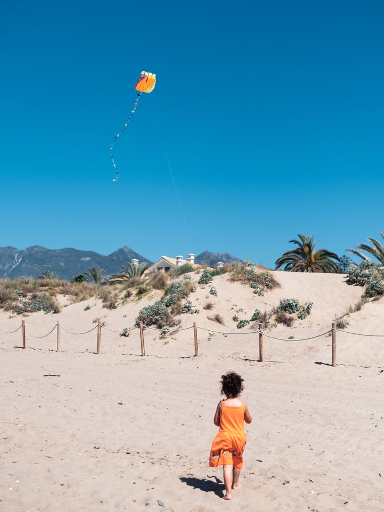 Toddler girl playing with kite on sandy beach