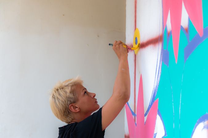 Blonde woman painting in colors on wall