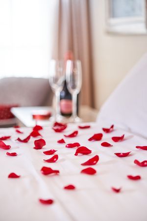 Comfortable bed with bedclothes covered with rose petals