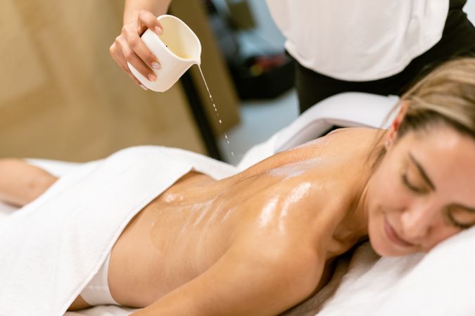 Woman having massage oil poured on her back