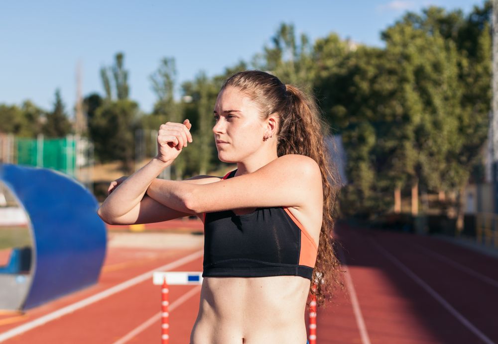Female athlete stretching on an athletics track.