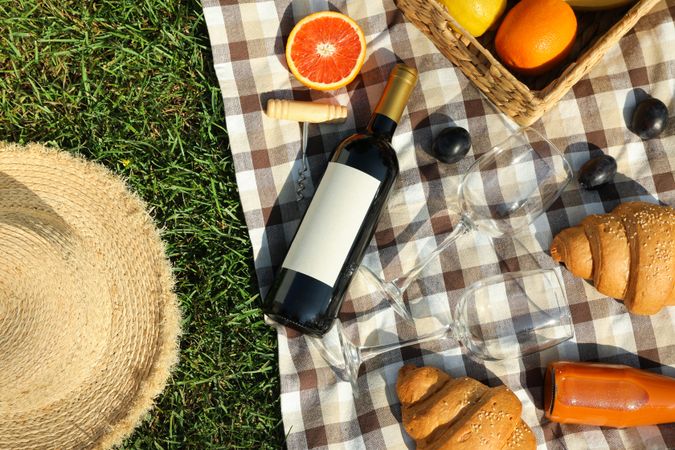 Composition with wine, croissants, fruits and towel on grass, top view