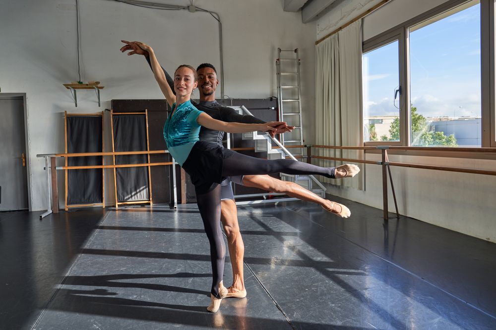 Couple of Black boy and white woman in a class doing a training in ballet academy