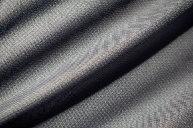 Wavy dark grey fabric background texture. shiny, glossy and elegant background.