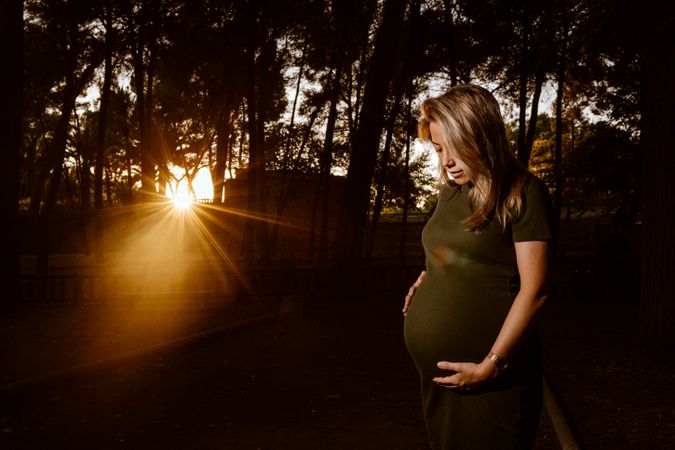 Charming pregnant woman standing on walkway in park