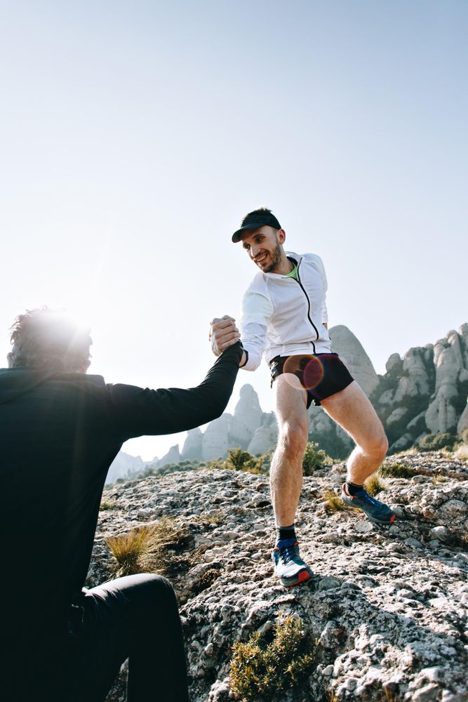 Man reaches hand out to help friend up